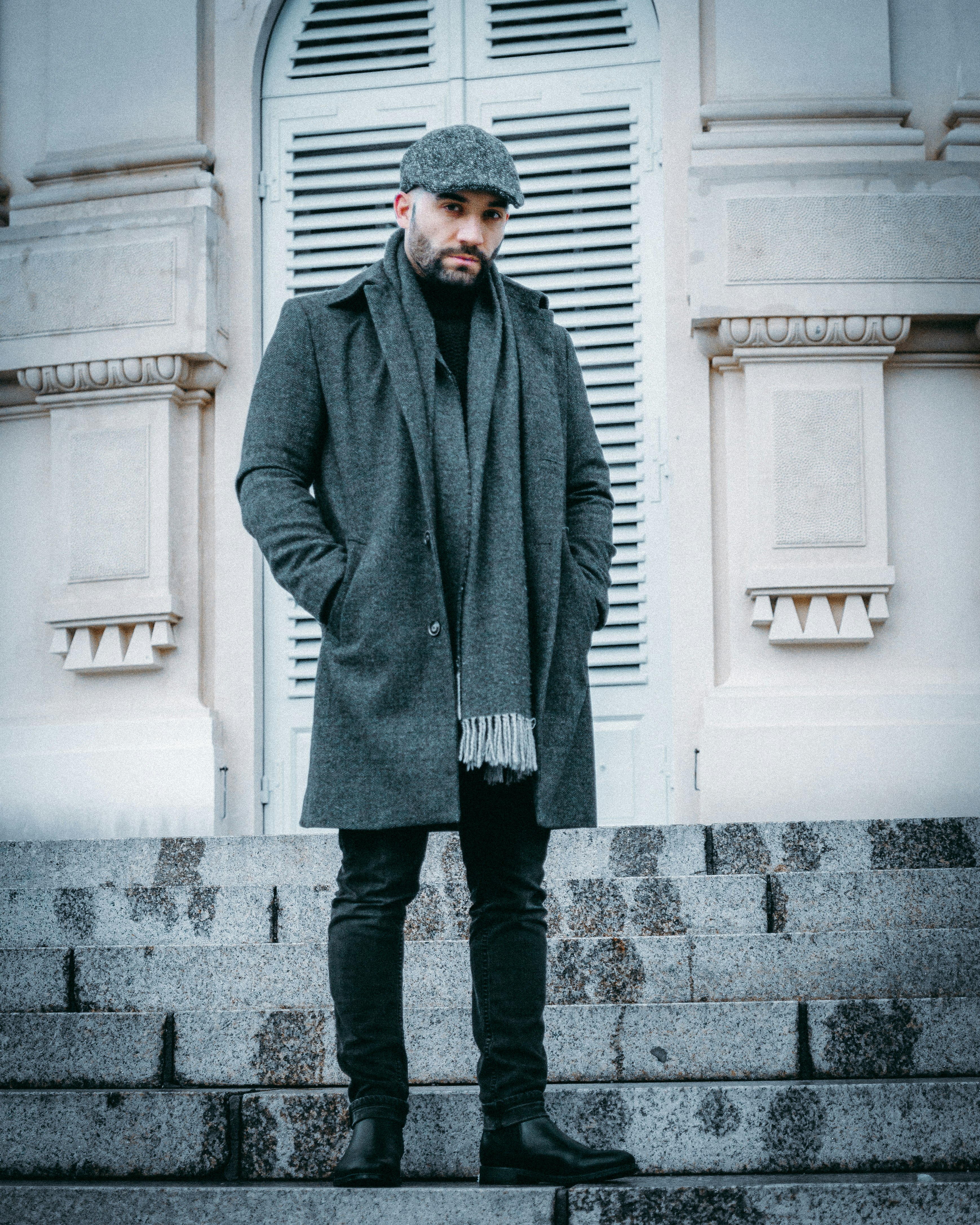 man in gray coat standing on gray concrete floor during daytime